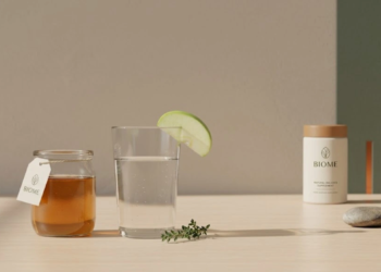 Glass of diluted apple cider vinegar with fresh apples on a kitchen counter.